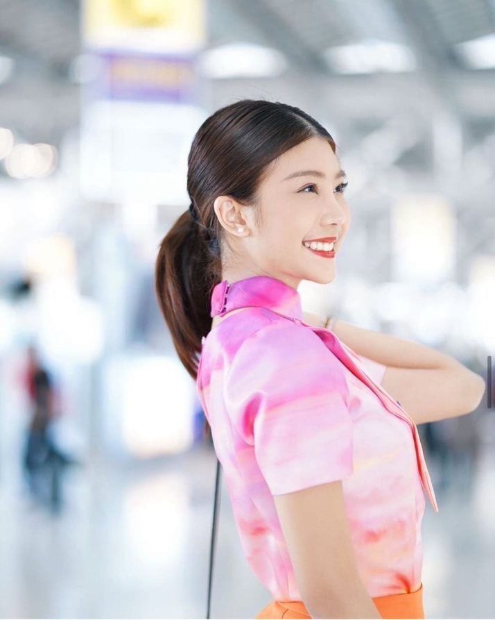 Female flight attendant in pink uniform and a ponytail