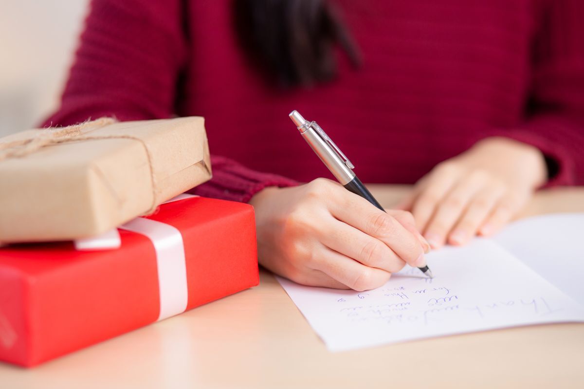 Asian woman writing a note on a Christmas card