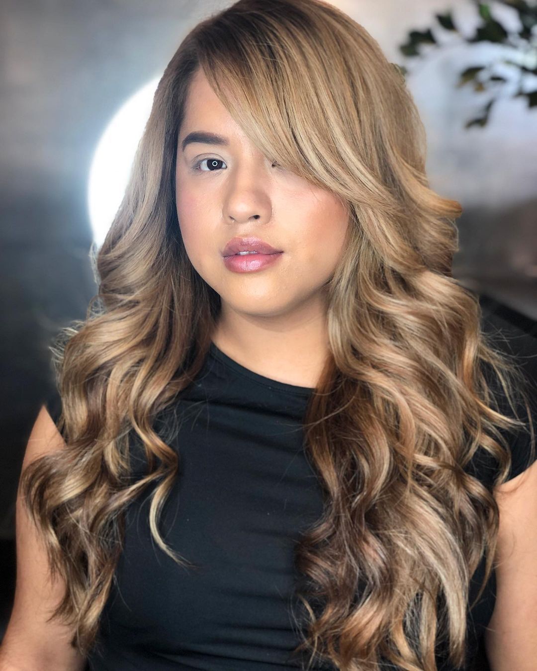 Woman with long, blonde, wavy hair and side-swept bangs.