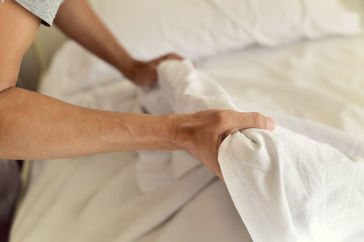 Man changing white bed sheets 