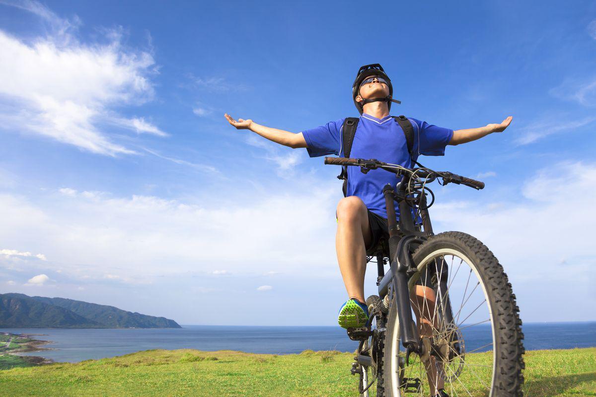 Asian man sitting on bike on a mountain 