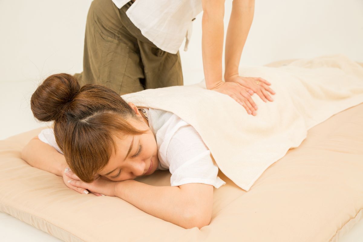 Woman enjoying a shiatsu massage on a mat.
