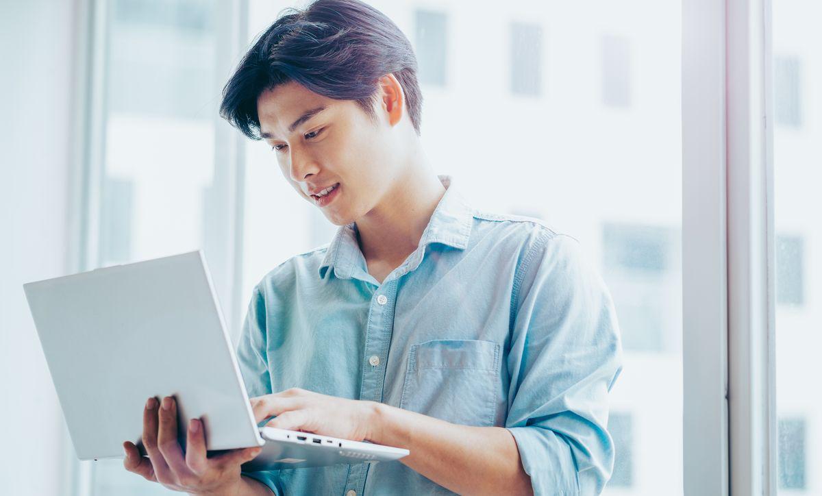 Asian man looking at laptop