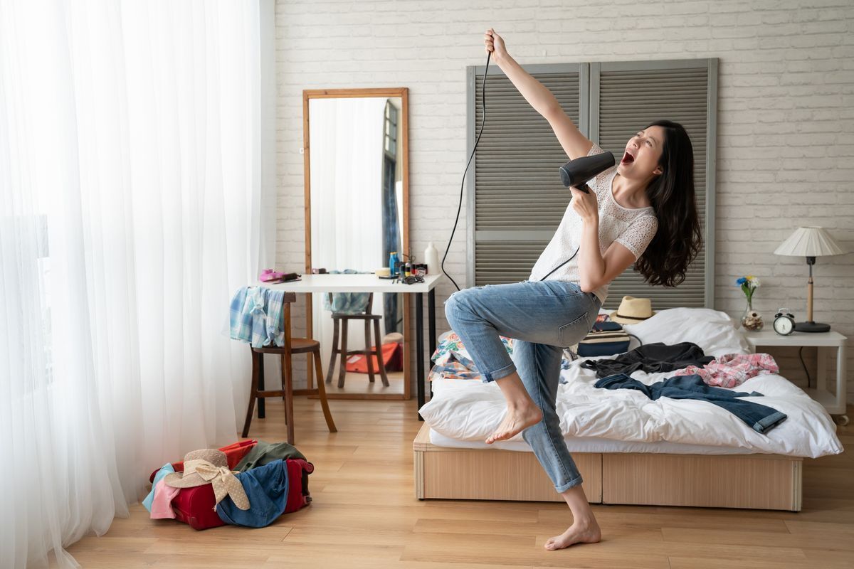 Girl dancing in her bedroom, singing into a hairdryer.