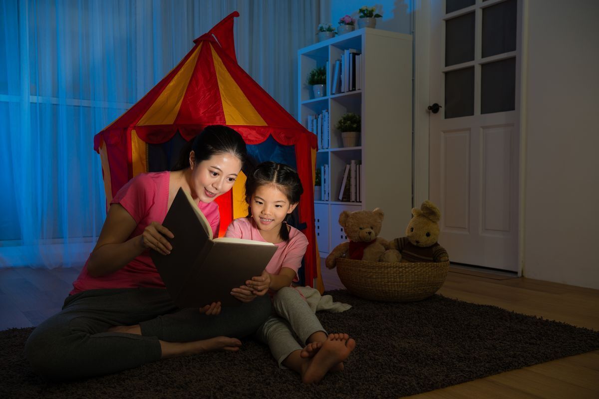 Mom reading book to child at night.