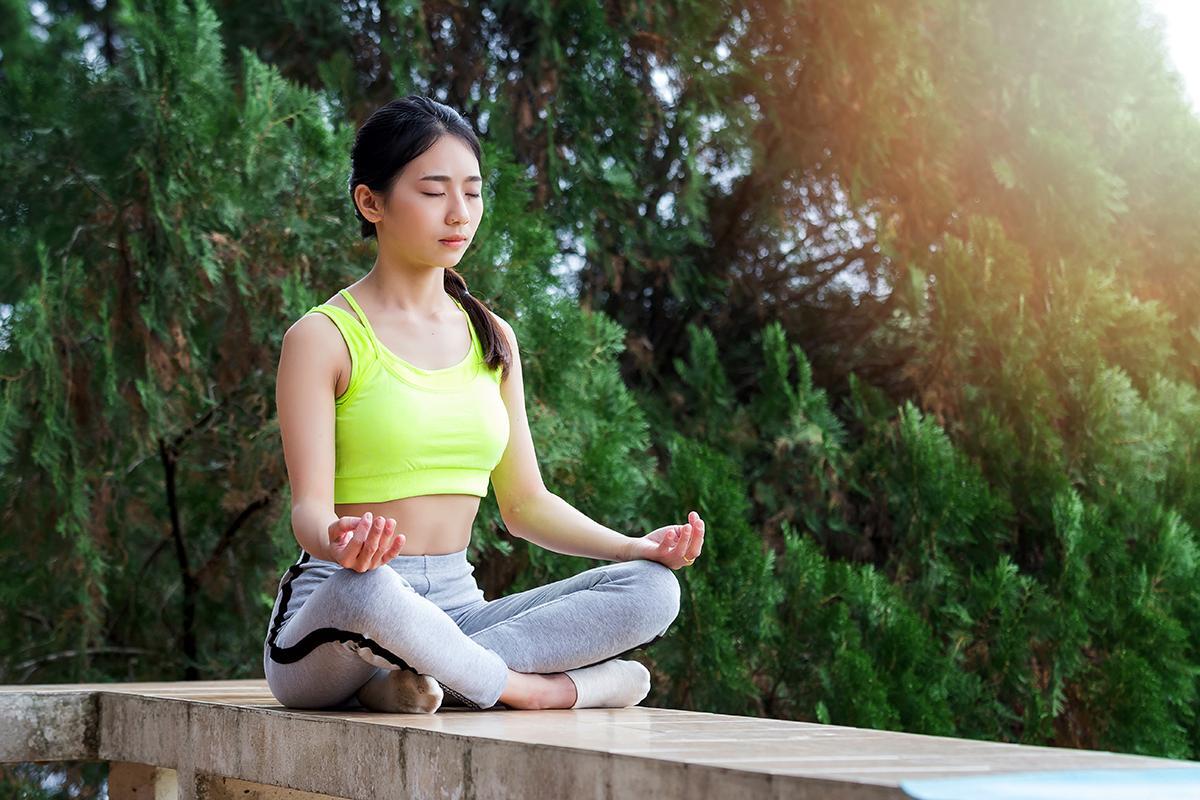 Young woman meditating outdoors in sportswear