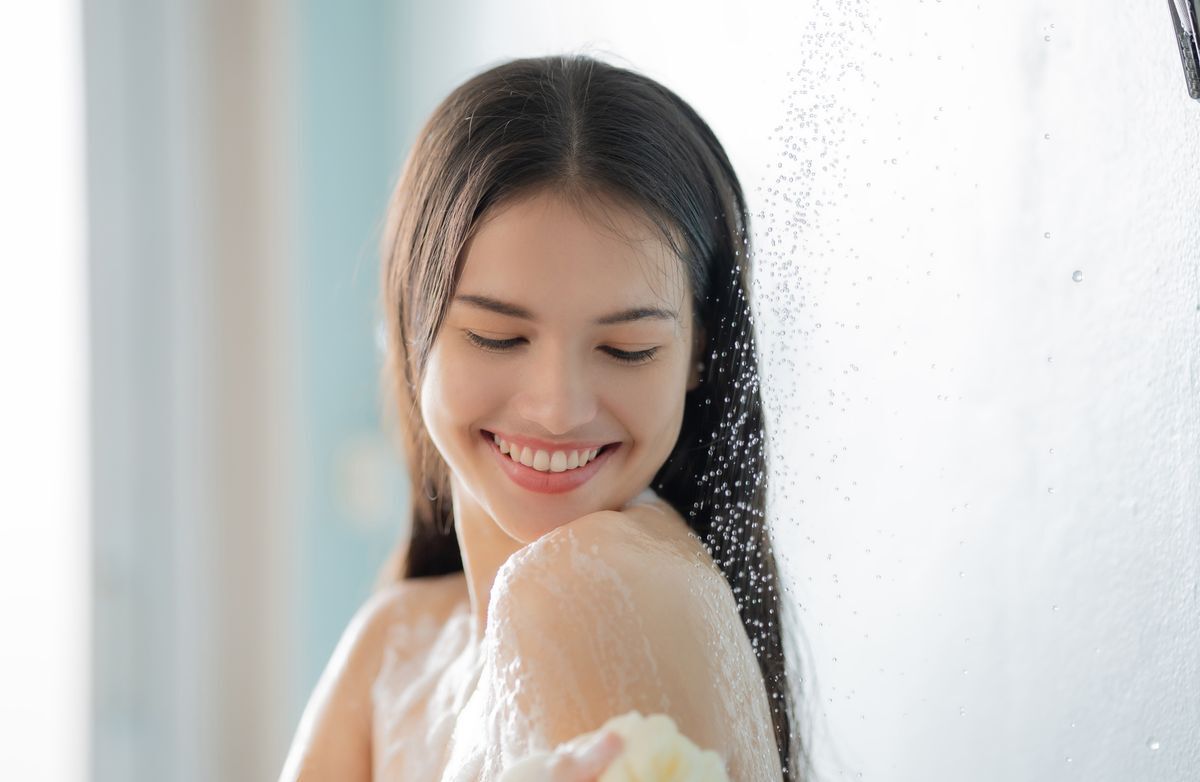 An Asian woman taking a shower and cleaning her body with soap 