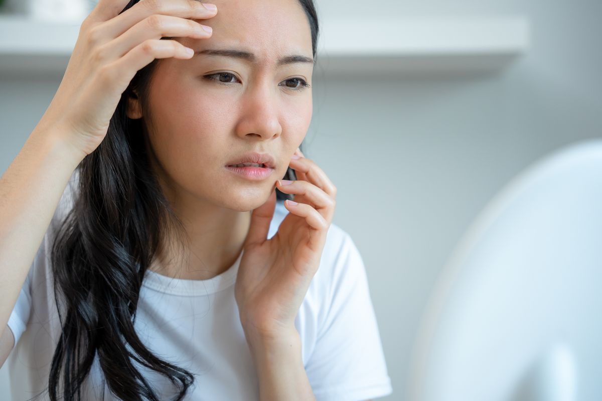 Asian woman worried while looking in the mirror