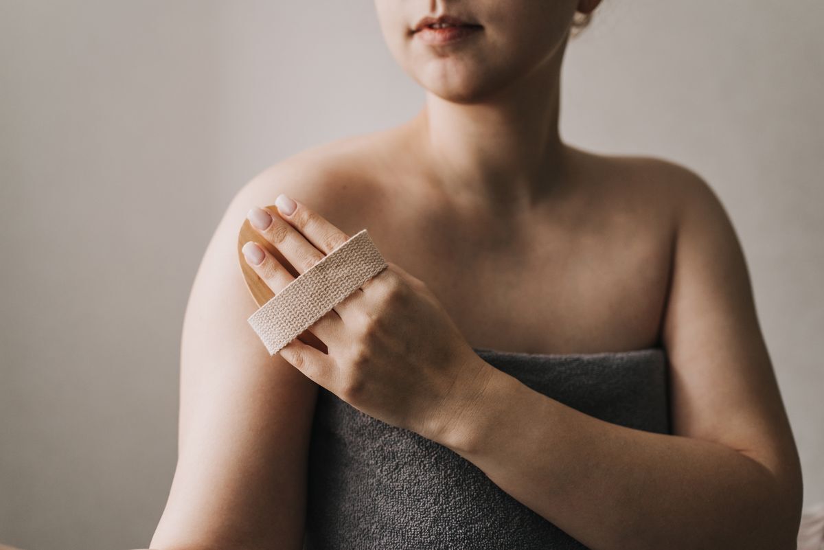 Asian woman in a towel dry brushing her skin