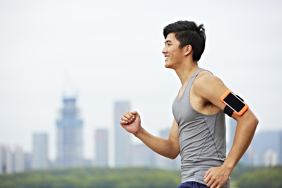 An Asian man jogs in an outdoor location.