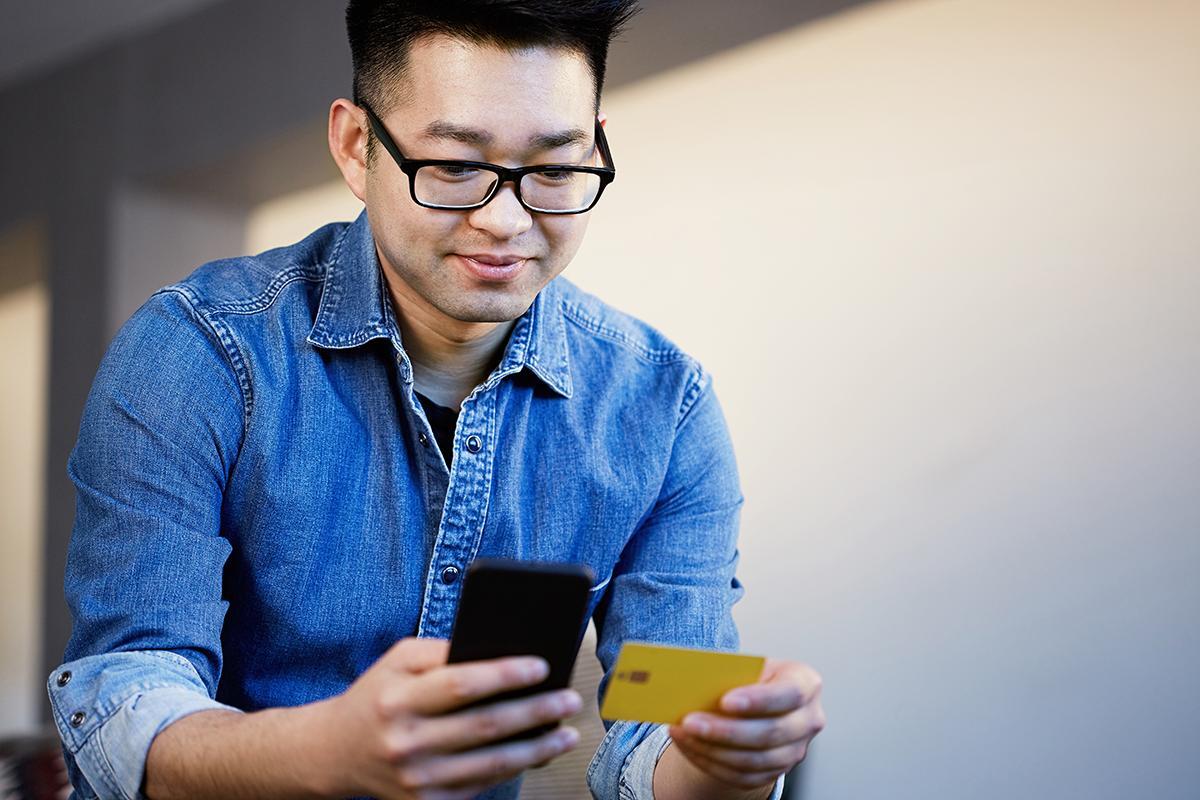 Young Asian man holds a credit card in his hand.