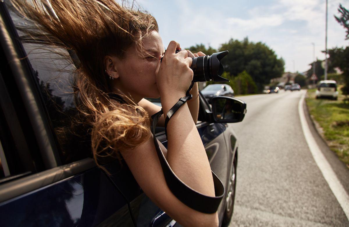 Young woman with messy hair taking photo from inside a car 