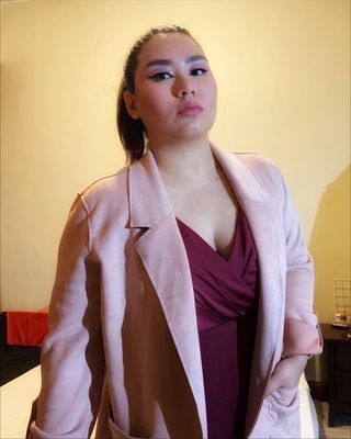 Asian woman wearing a pink blazer.