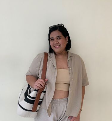 Asian woman with short hair wearing a crop top and beige shirt and shorts.