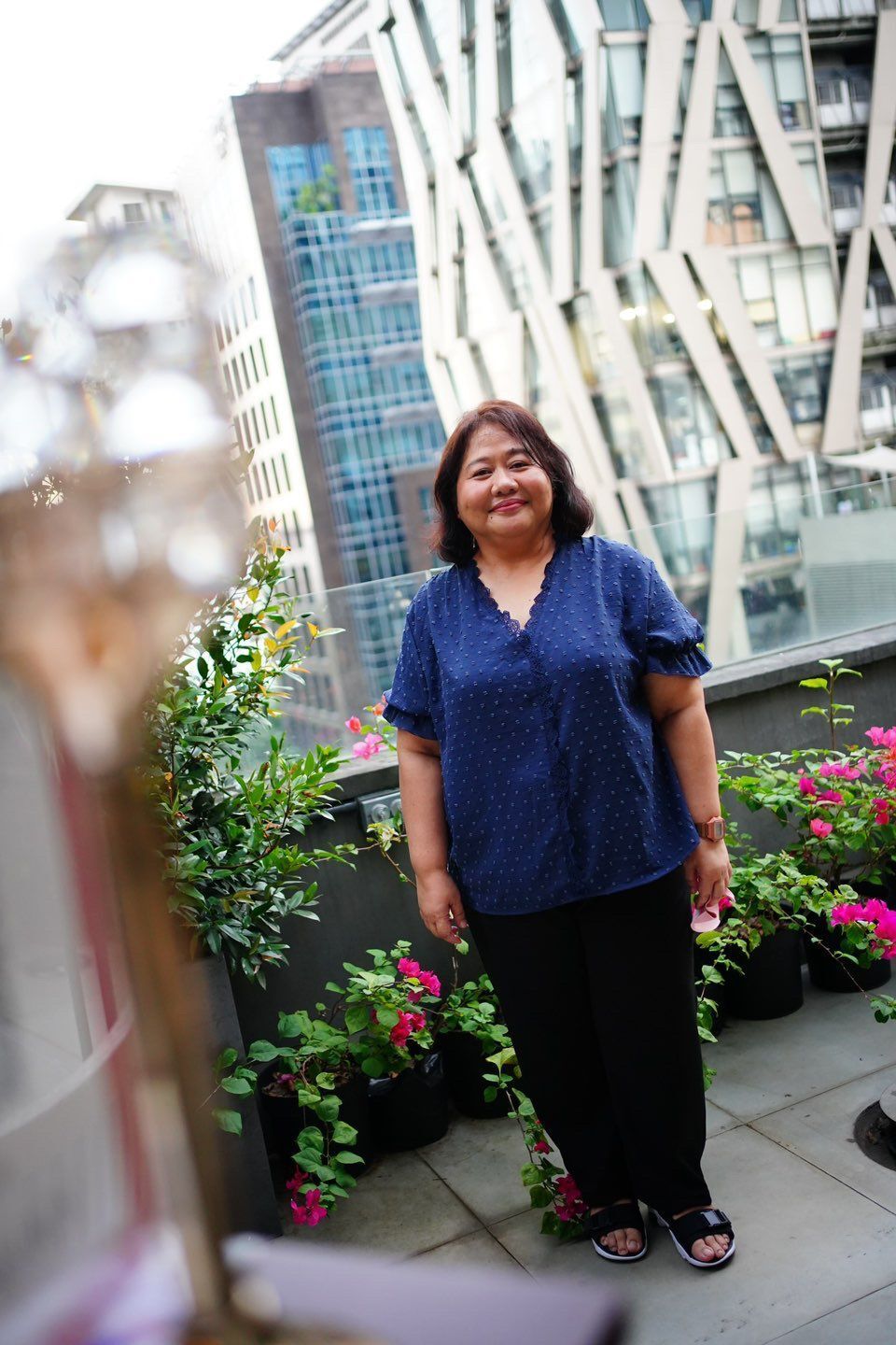 Asian woman wearing a blue shirt posing outdoors.
