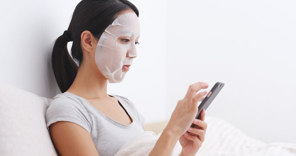 An Asian woman with a face mask on while using her smartphone