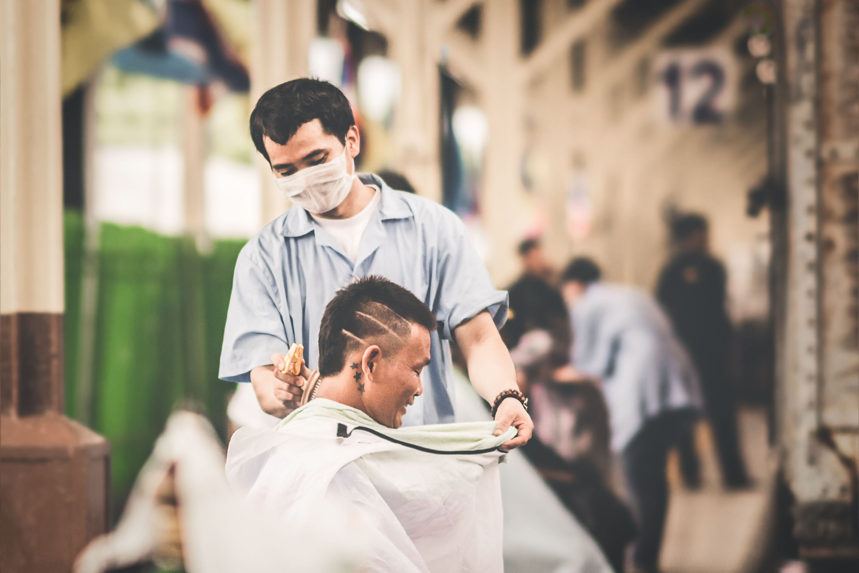 Asian barber brushing hair off neck