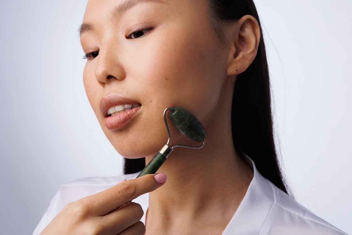 An Asian woman massaging her face with a stone facial roller.