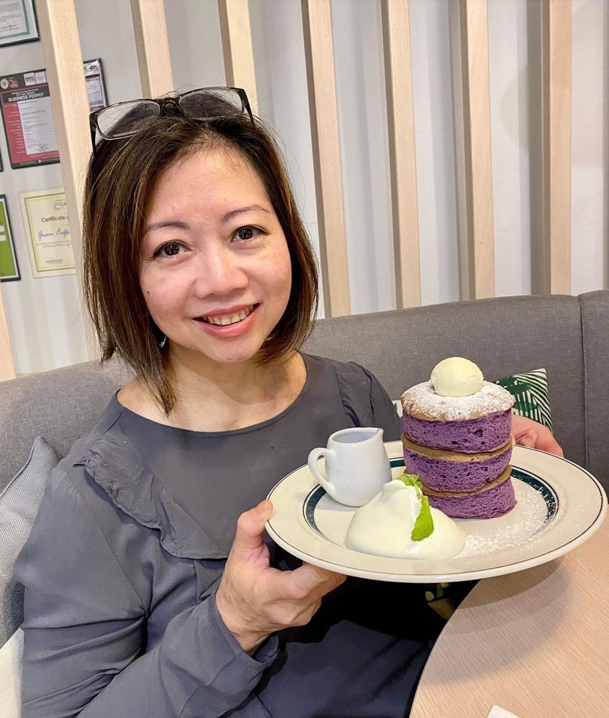 Asian woman happily holding up a plate of cake. 