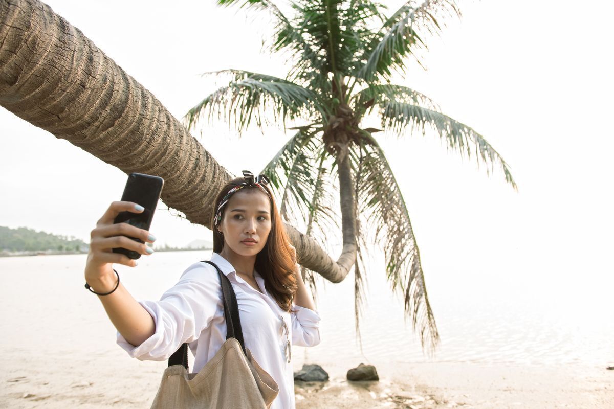 Asian woman taking a selfie by the beach