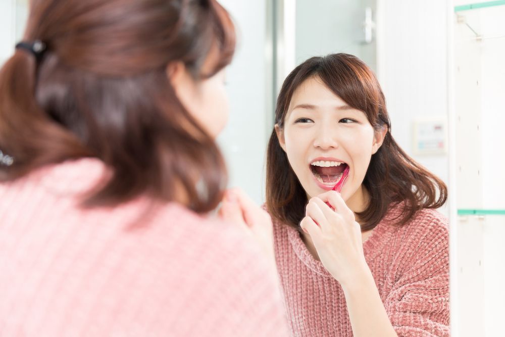 A young woman brushing her teeth in front of a mirror