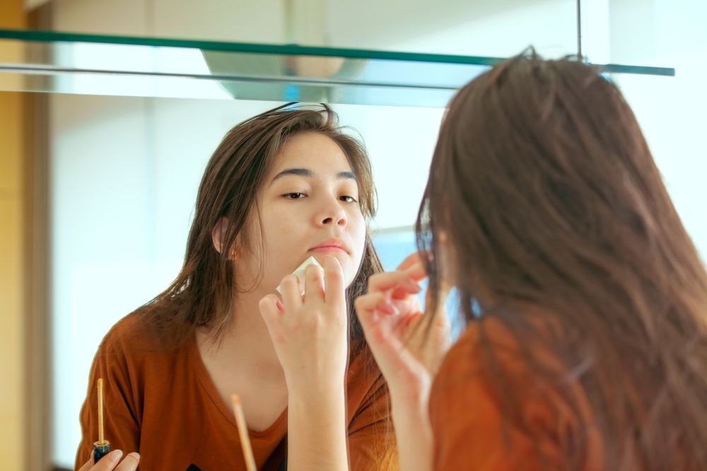 Woman blending foundation on her chin with makeup sponge.