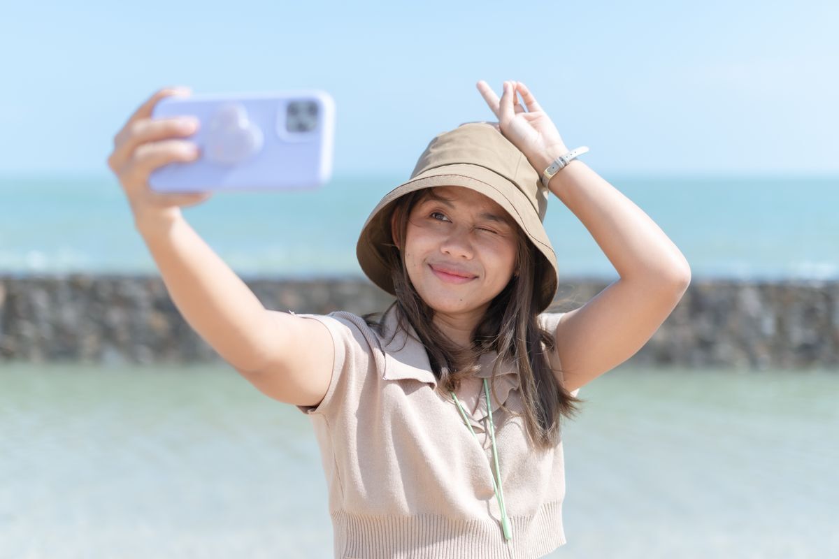 Asian girl taking a selfie by the ocean 