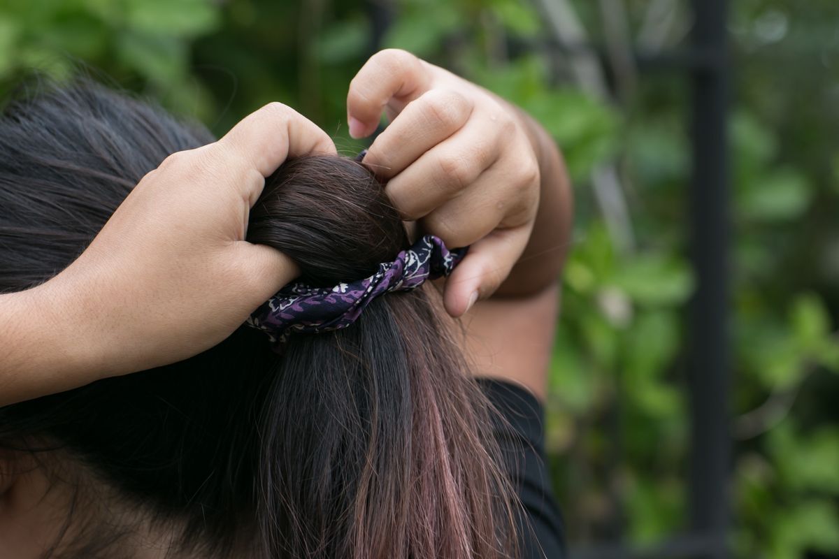 Asian teen tying hair with a scrunchie