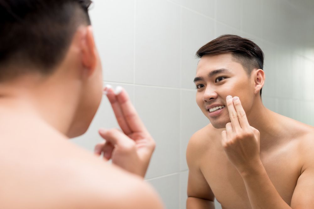 A man looking at the mirror washing his face.