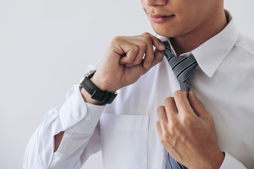 A man getting ready wearing his tie.