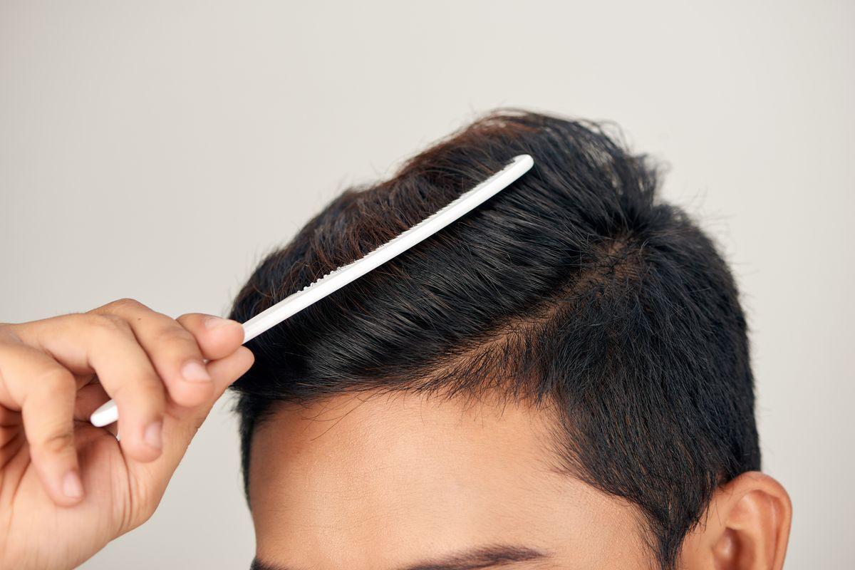 Asian man combing hair to one side 
