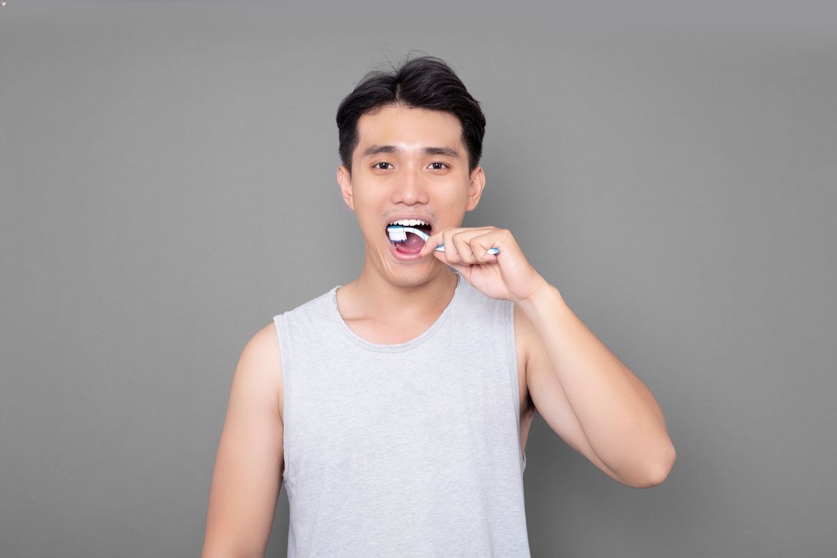Asian man brushing teeth in tank top
