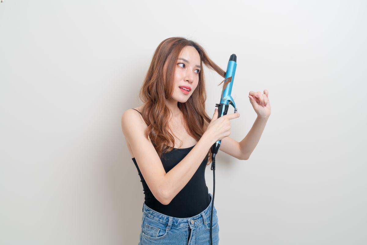 Woman styling hair with a curling iron 