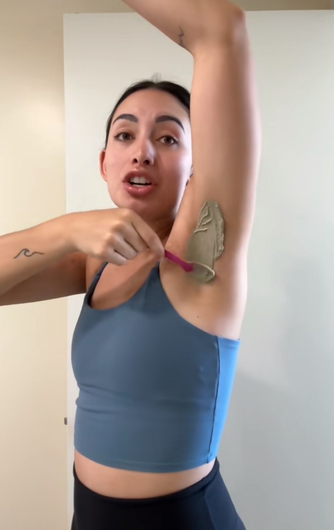 Woman applying clay mask to her armpit.