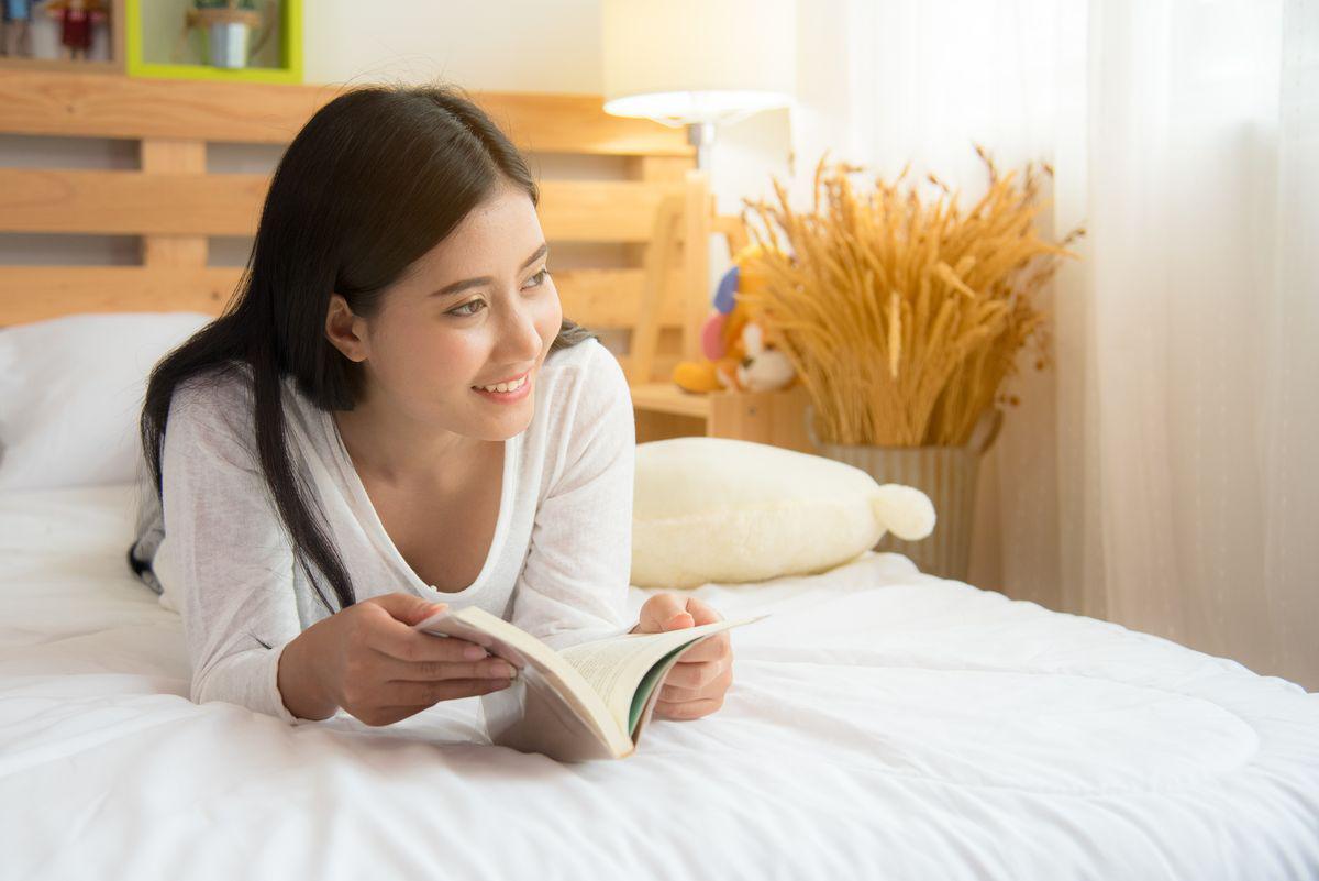 Asian woman reading in bed 
