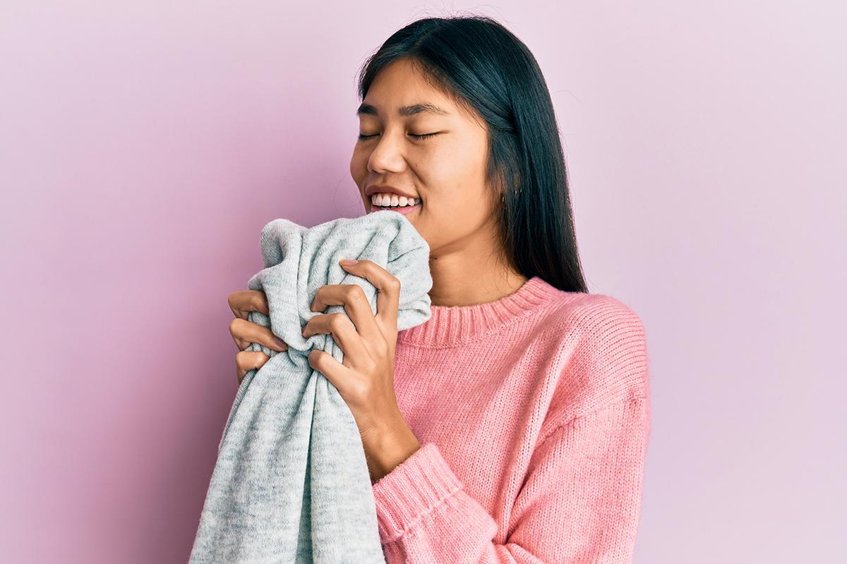 Asian woman in pink sweater holding gray fabric