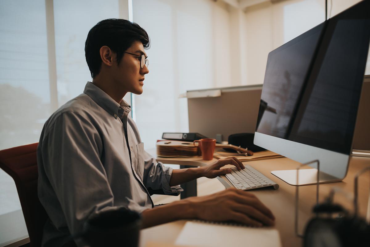 Asian man looking at blank computer
