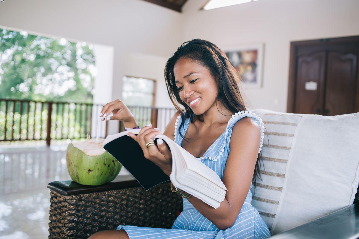 Asian woman drinking coconut and reading