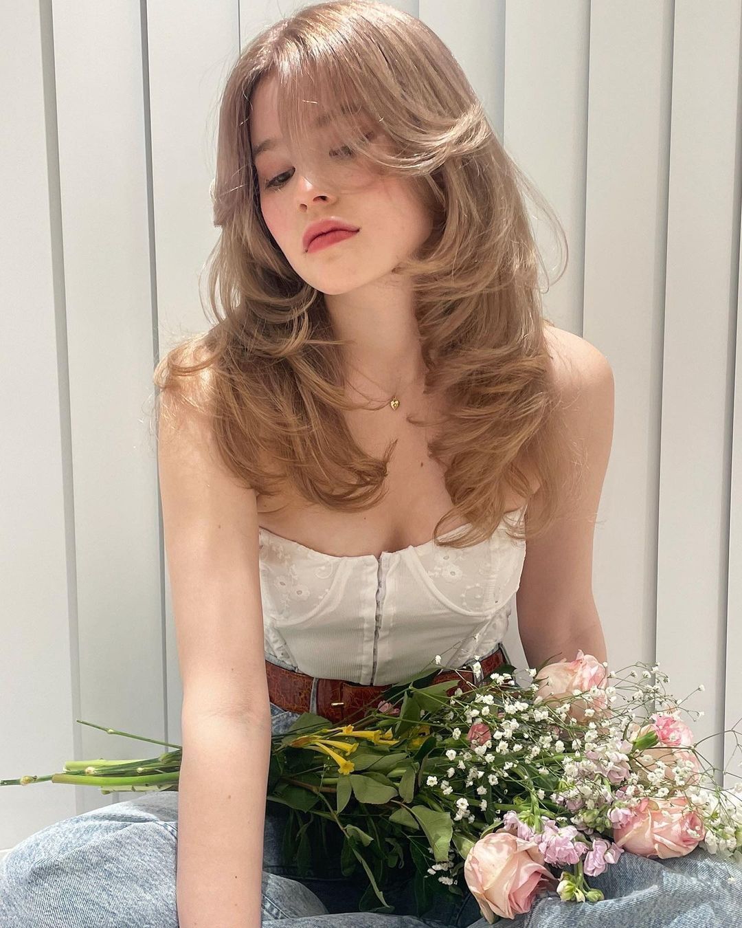 Woman in white corset top with blonde butterfly cut.