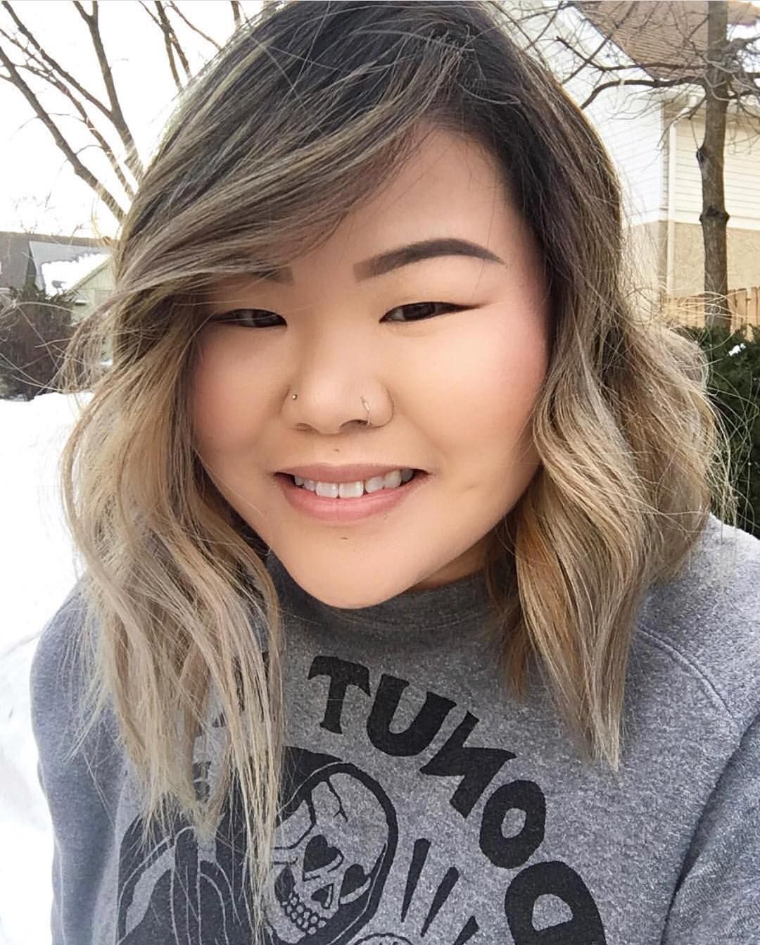 Woman in gray sweater with balayage asymmetrical lob.