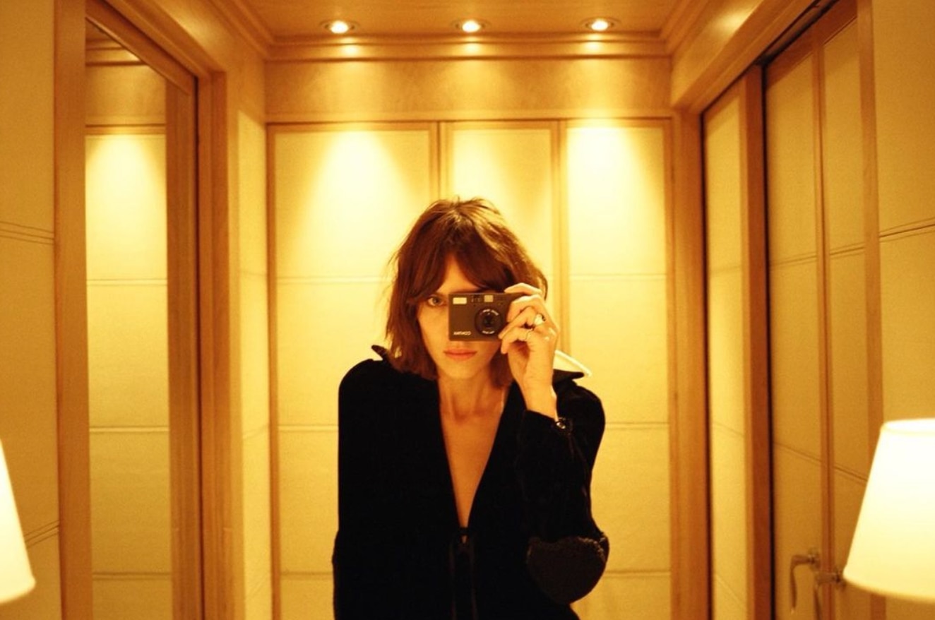 Alexa Chung shaggy hair and curtain bangs, taking a mirror self portrait. 