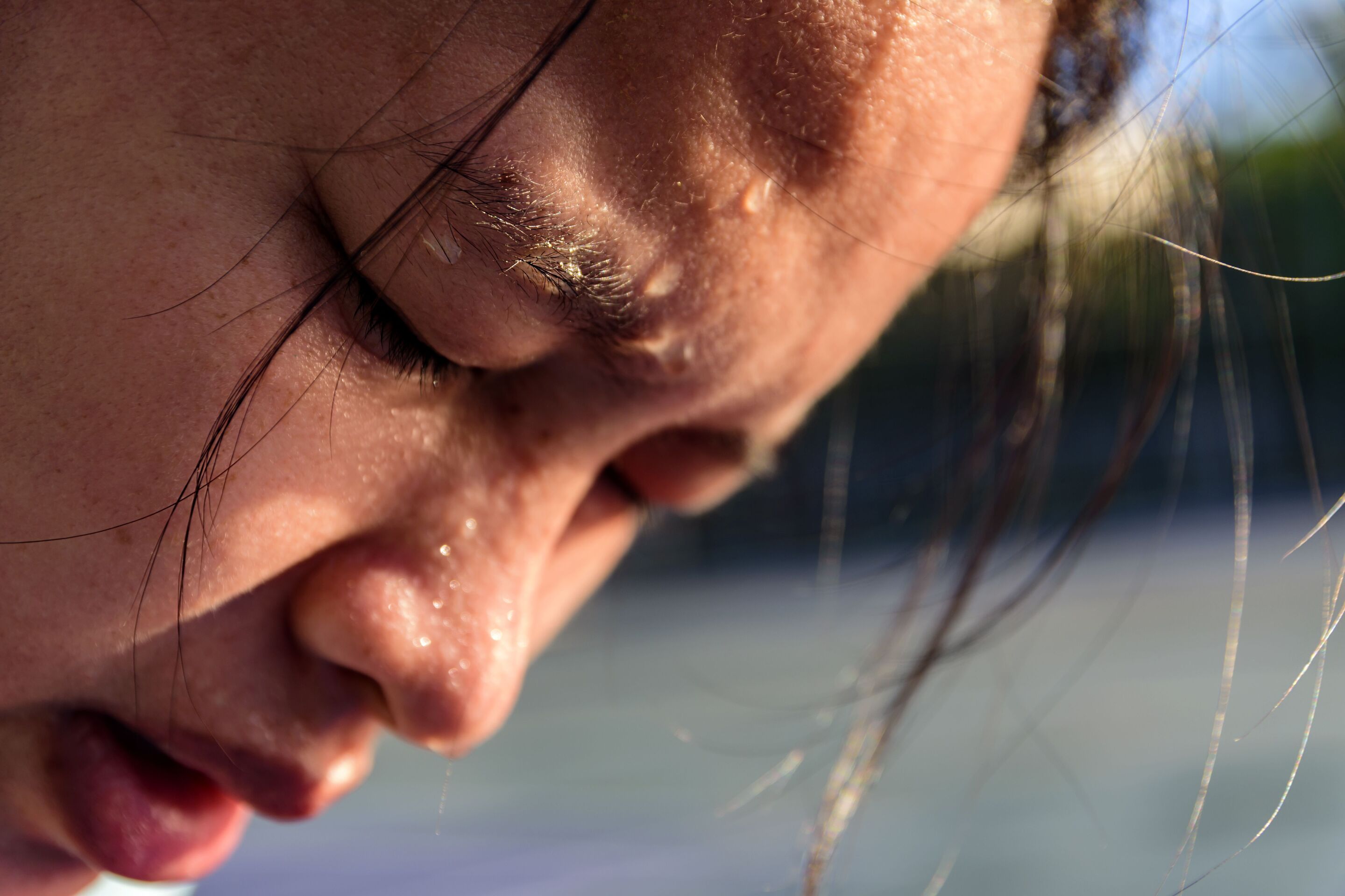A close up of an Asian woman’s face sweating