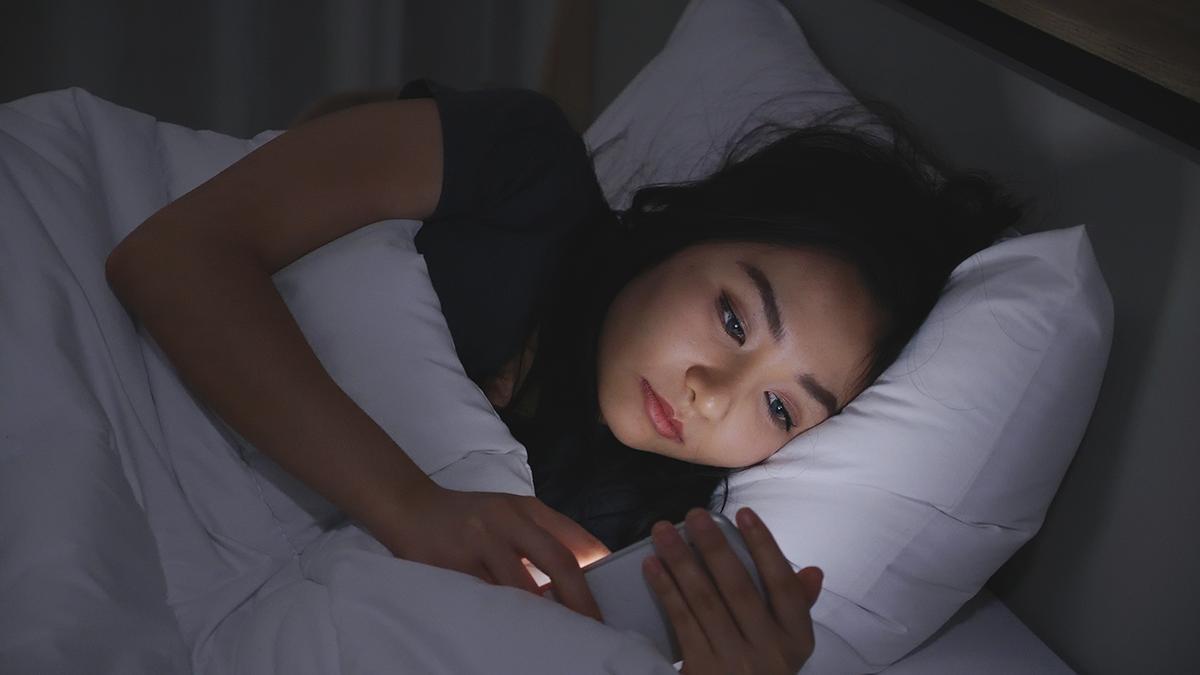 Asian woman looking at phone in the dark