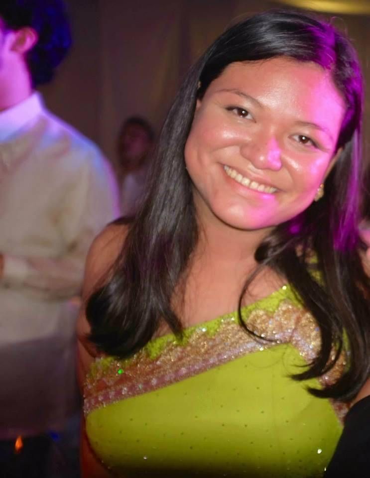 Asian woman in green beaded gown smiling in a formal event.