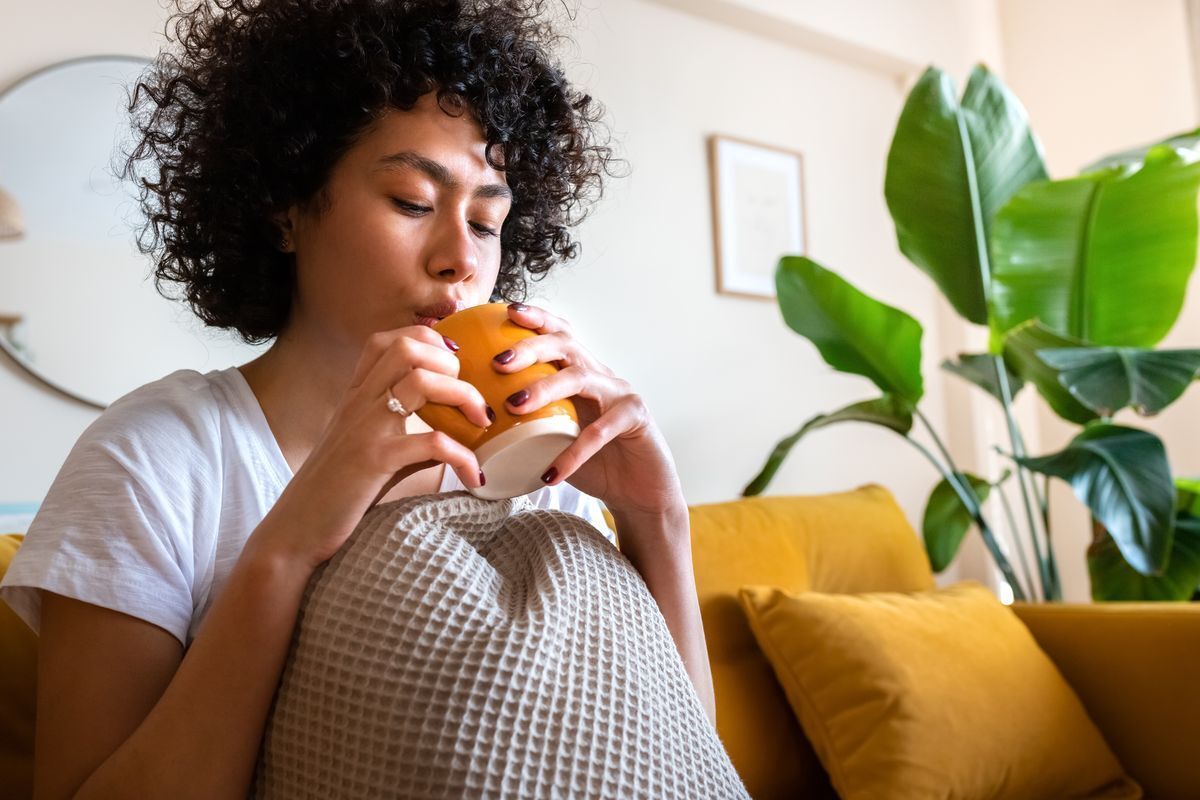 A woman drinking herbal tea in a cup.