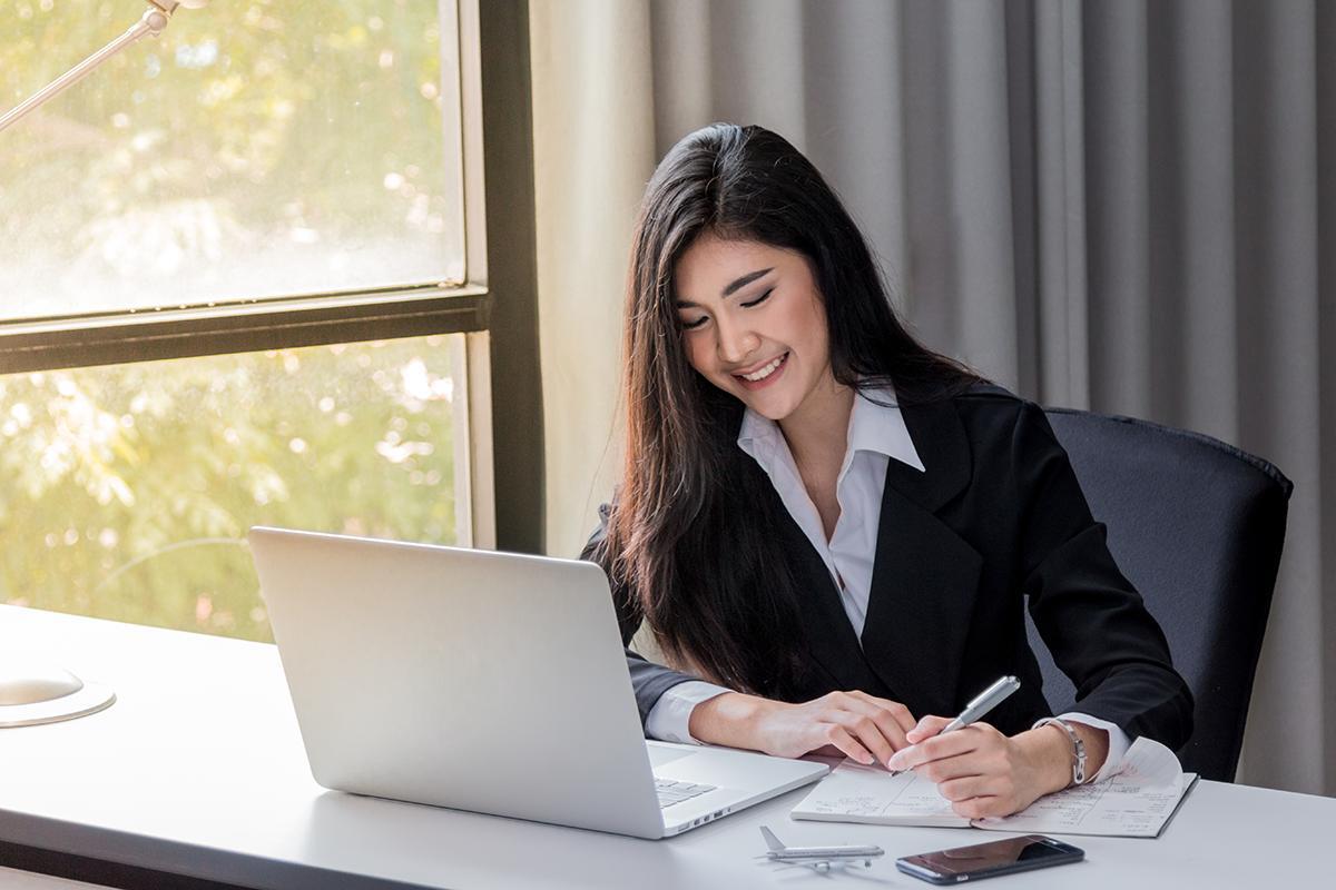 Asian woman in suit working in front of laptop