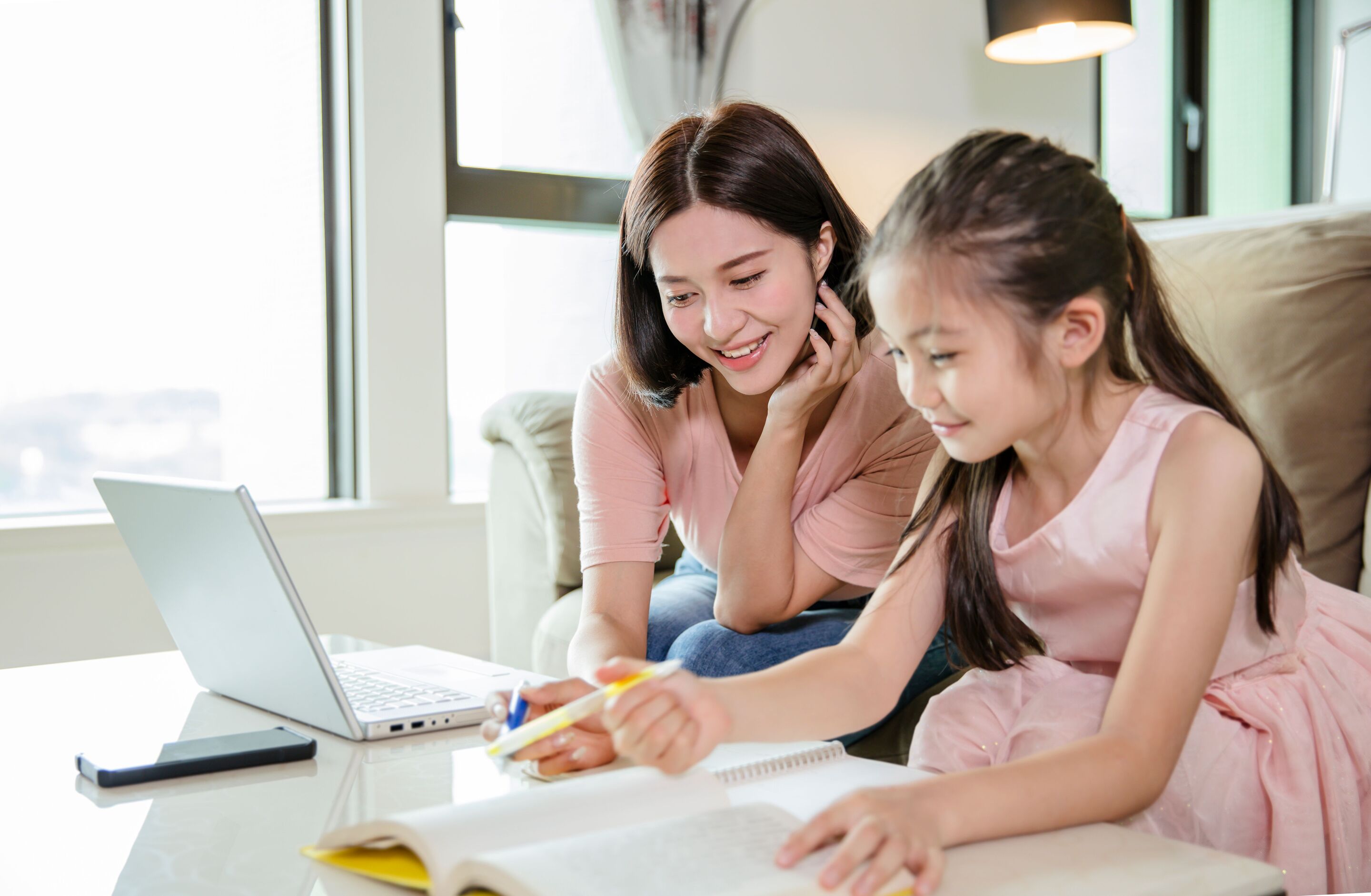 Mom and daughter working together using a notebook and a laptop