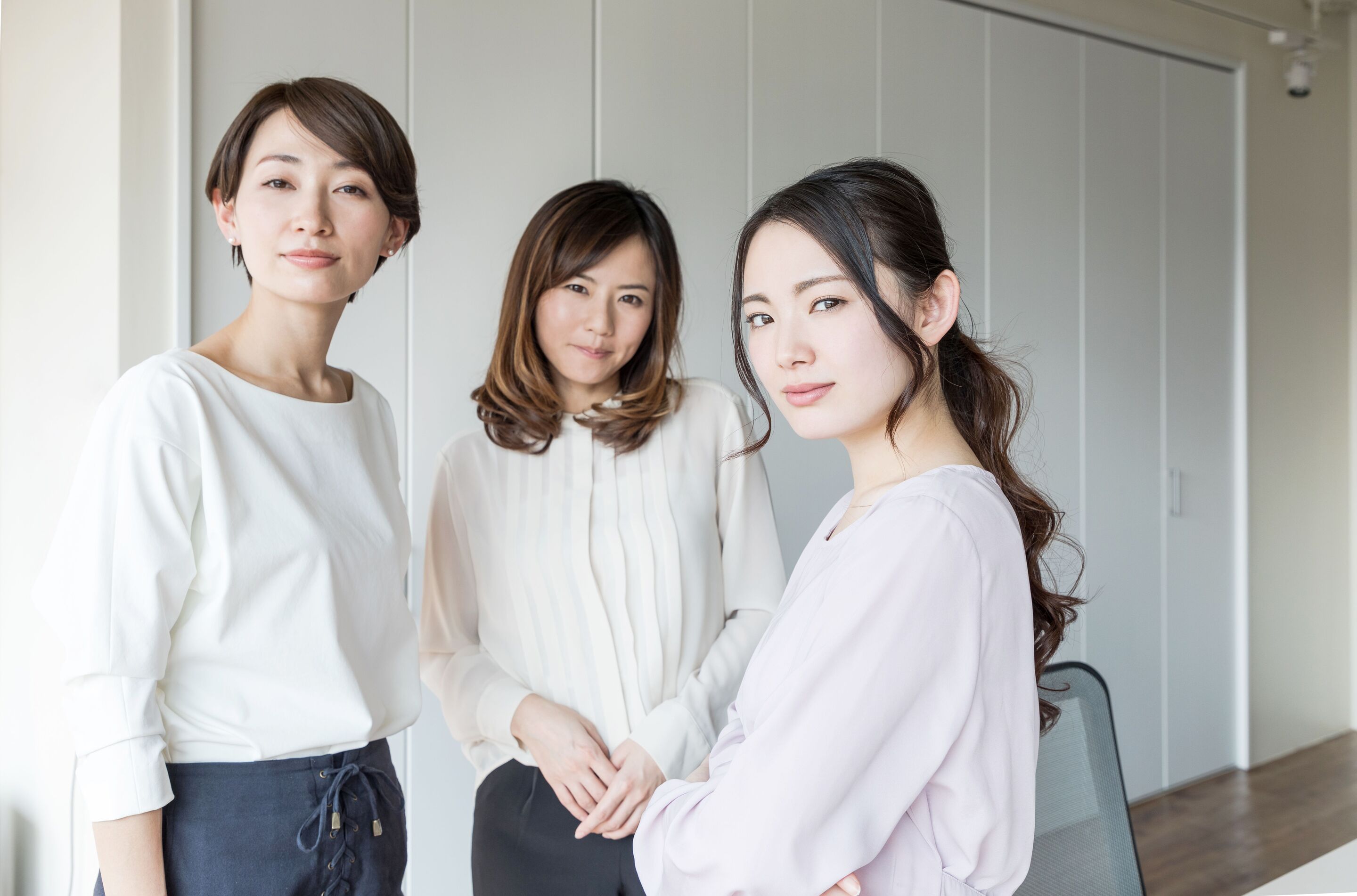 Three Asian women wearing white blouse looking fiercely into the camera