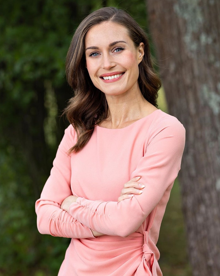 Finnish prime minister Sanna Marin in a salmon pink dress with arms crossed. 