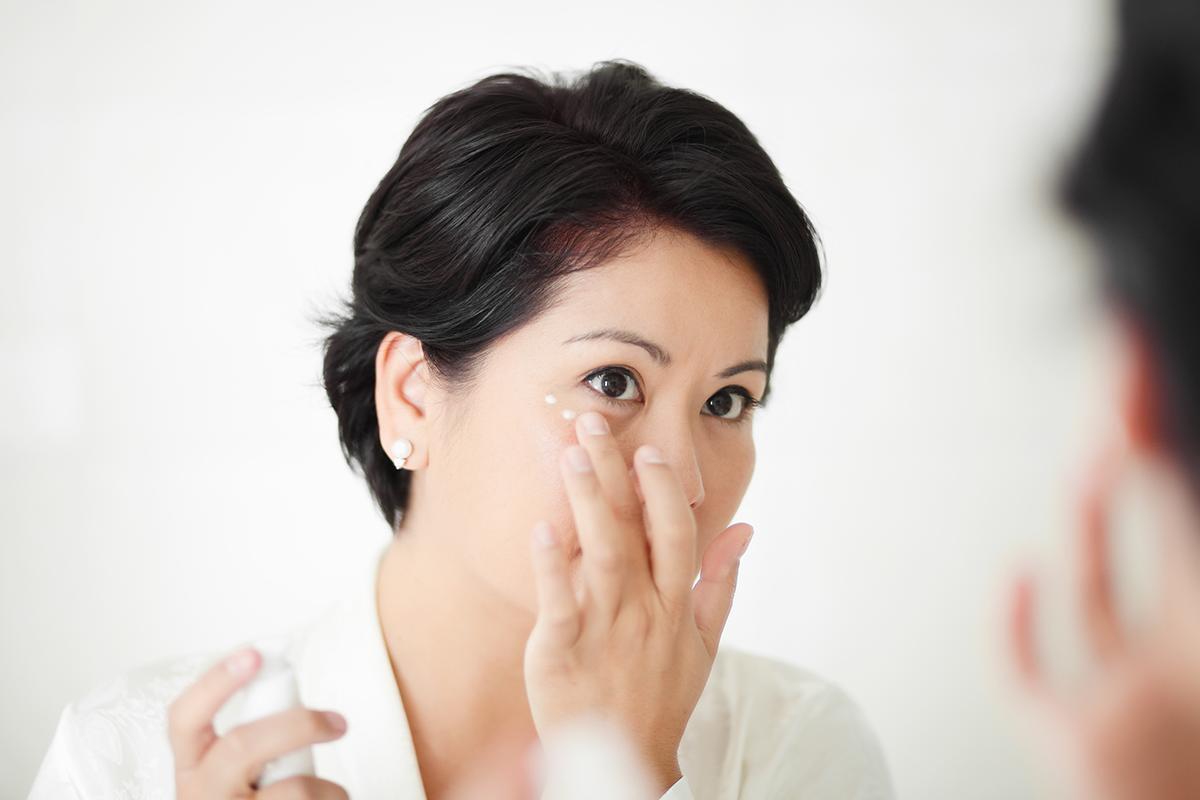 Asian woman applying eye cream